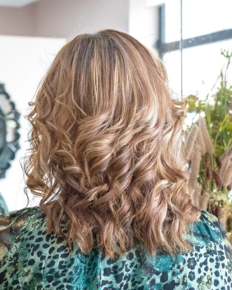 Cabelo loiro pelos ombros, com ondas largas, visto de costas no salão.